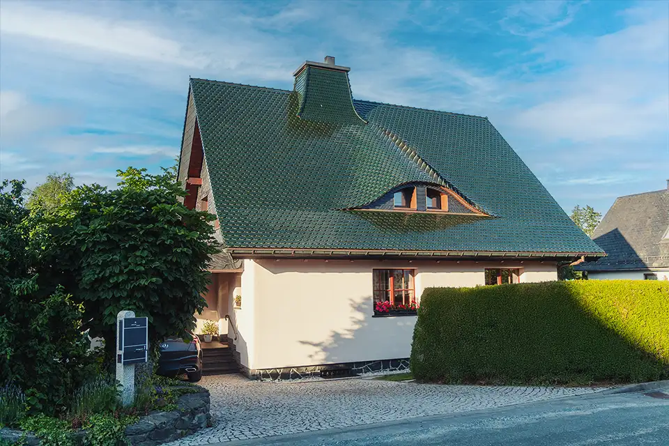 House with a dark green roof shaped like an eye with window 'pupil' and a cream exterior.