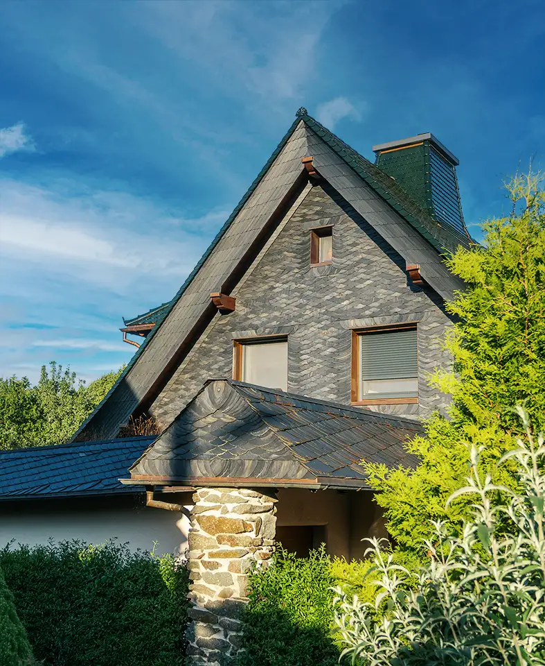 Wood-framed window set in dark slate-tiled roof with copper edging on a building under scaffolding.